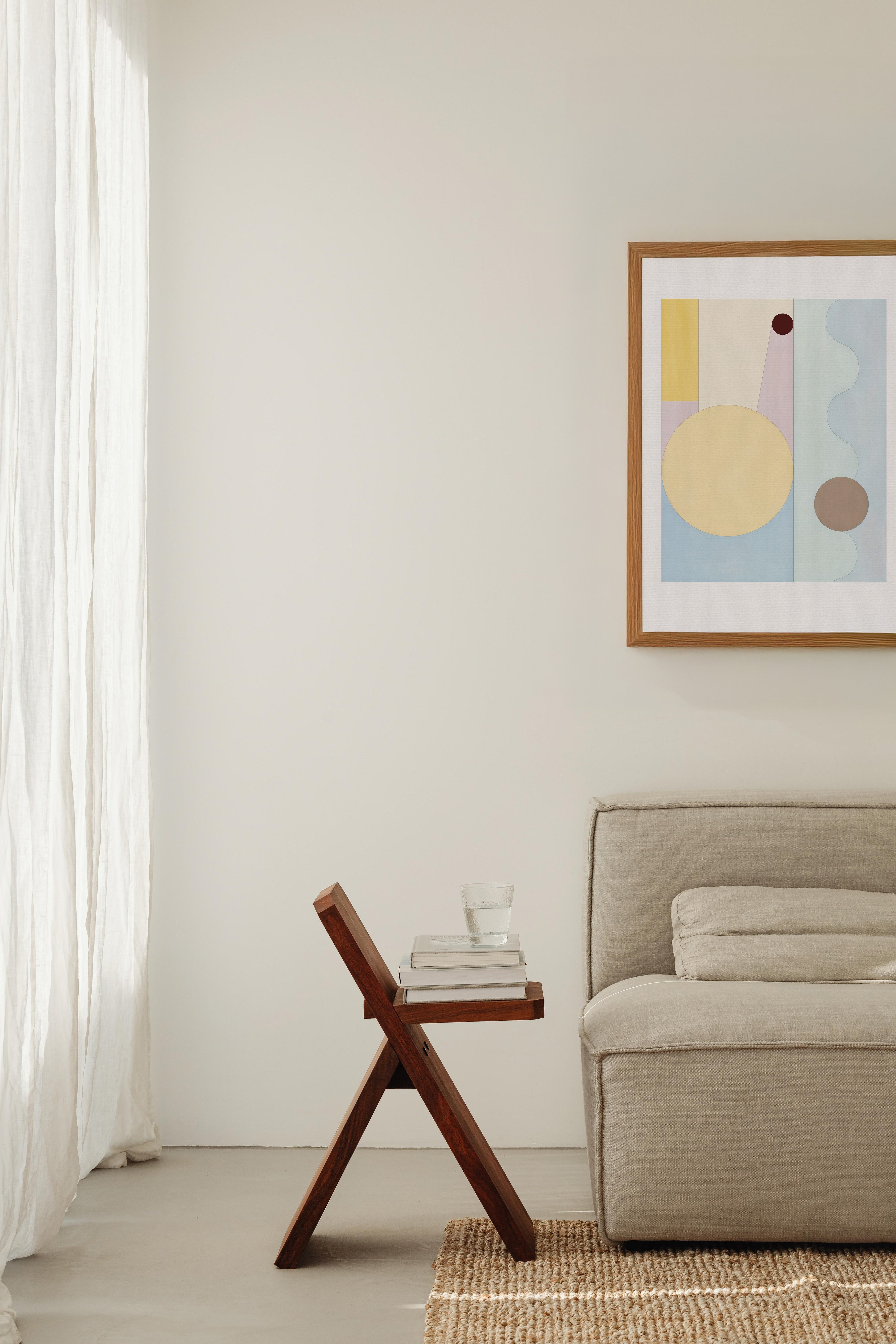 Modern living room with a beige sofa, wooden side table, and abstract art on the wall.