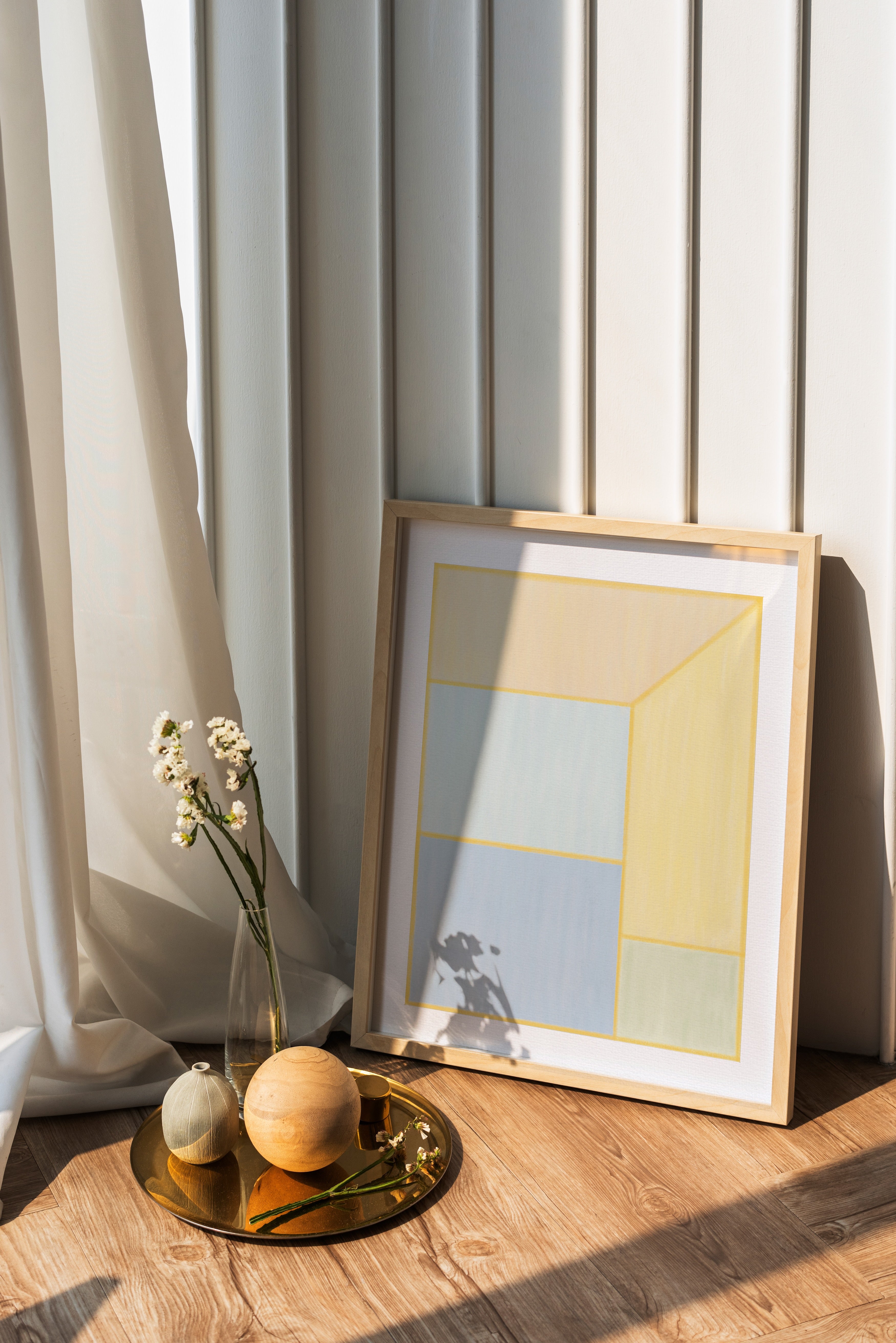 Framed abstract art on a wooden surface with decorative items and curtains in the background