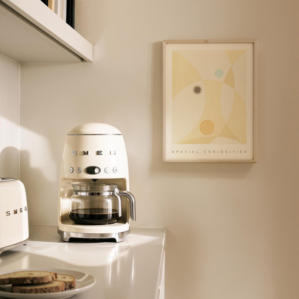 Vintage-style coffee machine on a kitchen counter with a framed picture on the wall.