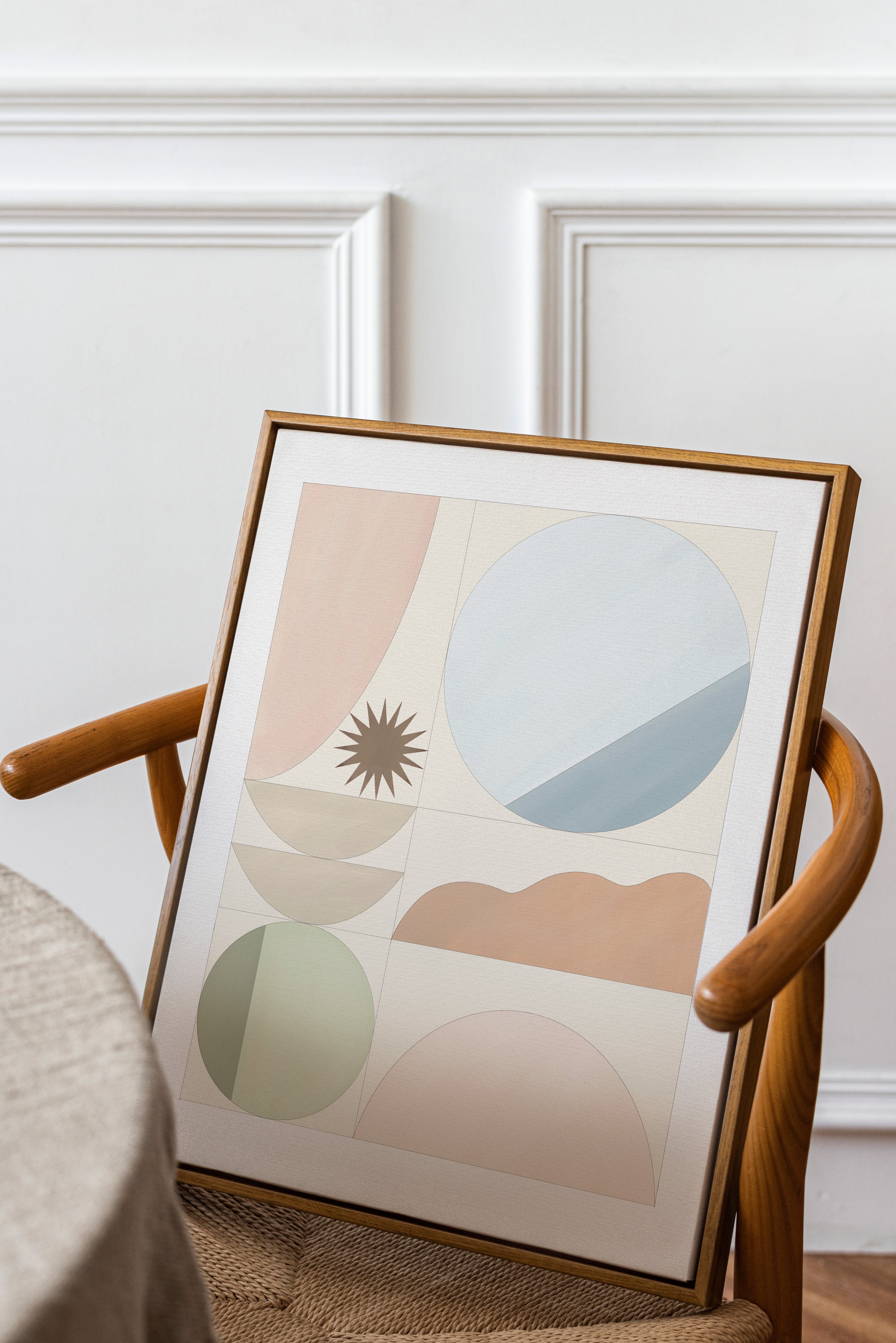 Framed abstract art print on a wooden chair against a white wall