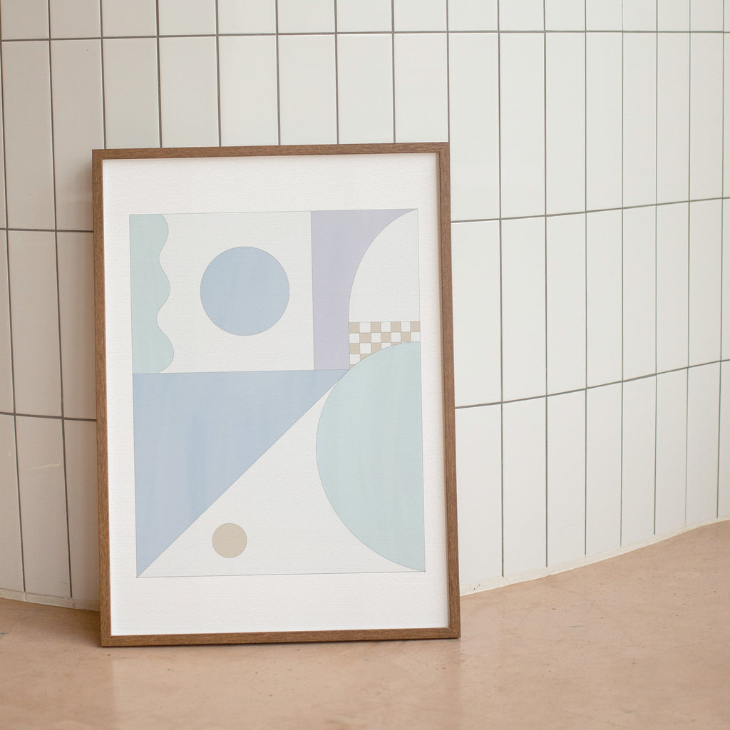 Framed abstract art print with geometric shapes on a tiled wall.