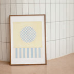 Framed abstract art print with geometric patterns on a tiled wall.