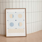 Framed abstract art print with geometric shapes on a tiled wall.